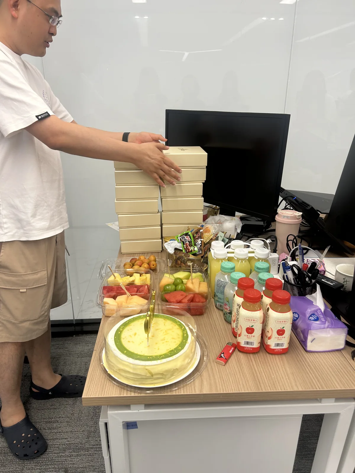 办公桌上摆开的蛋糕、果切和一排饮料