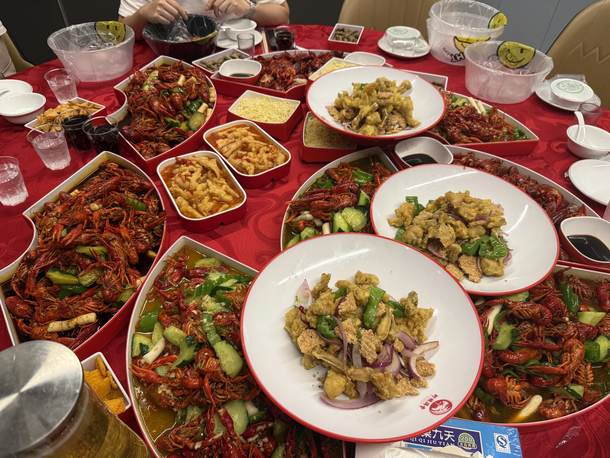 铺满整桌的小龙虾和各式炒菜，中间还叠着一盘菜